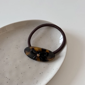 Macro de l'élastique à cheveux en acétate avec nœud et strass sur assiette céramique