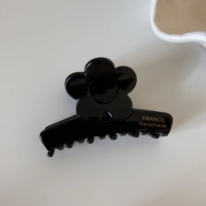 Détail de la pince à cheveux fleur noire en acétate avec inscription France Handmade dorée