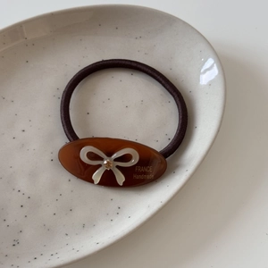 Détail de l'élastique en acétate avec un nœud blanc et un cristal étincelant