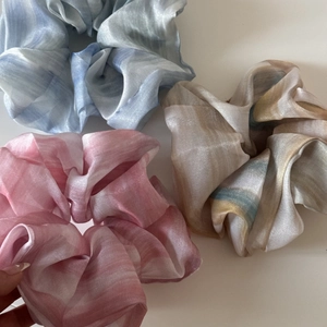 Detailed close-up of large chiffon scrunchies featuring soft marble dye and silk textures