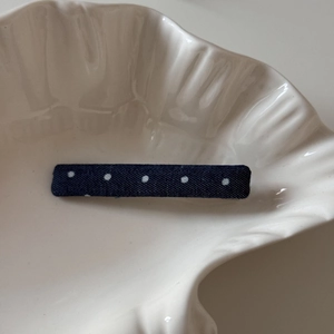 Détail de la barrette en denim bleu à pois blancs sur un plateau élégant