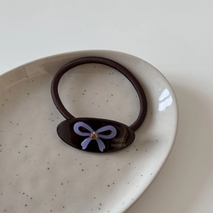 Vue détaillée d'un élastique à cheveux avec breloque en acétate et nœud en strass mauve