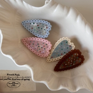 Détail de quatre pinces à cheveux en forme de cœur avec strass colorés sur plateau