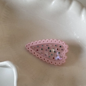 Détail d'une pince à cheveux en forme de cœur avec bord rose et strass multicolores