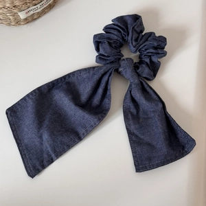 Dettaglio del tessuto in denim blu scuro dell'elastico per capelli con nastri lunghi