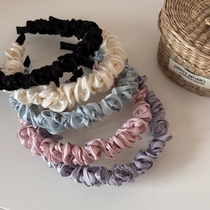 Detailed view of assorted satin scrunchie headbands in pastel colors and smooth silk texture