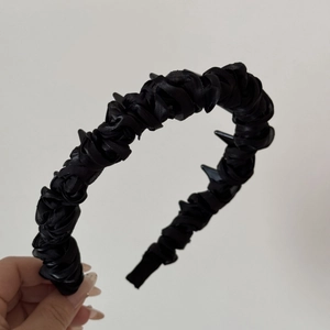Detail of black pleated fabric headband showing non-slip teeth and satin texture