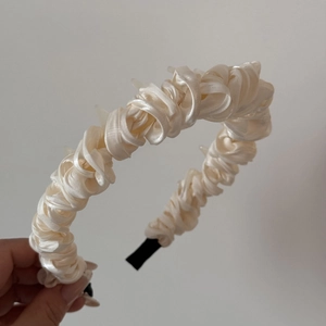 Detailed macro view of the cream pleated satin headband with spiral twisted design and non-slip tip
