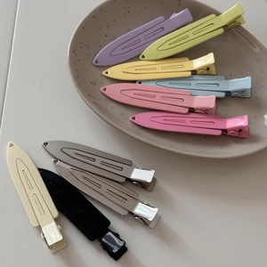 Colorful metal hairpins in macaron shades displayed on a ceramic tray for styling