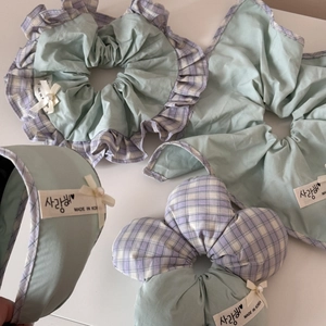 Close-up of mint green and purple plaid hair scrunchies with lace and bow details