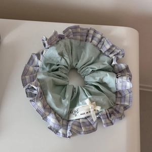 Detail of green and purple plaid scrunchie with a white bow and pearl decoration