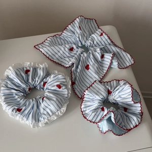 Détail de trois chouchous à rayures bleues avec broderie cœur rouge et bords en dentelle