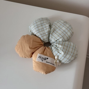 Detail of flower-shaped scrunchie featuring orange and blue plaid fabric with a pearl charm