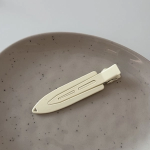Detailed view of matte cream yellow metal hair clip on a minimalist ceramic plate