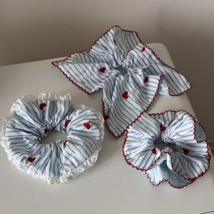 Lot de chouchous à rayures bleues avec broderie cœur rouge et bords à volants sur fond blanc