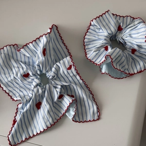 Détail d'un lot de chouchous à rayures bleues avec broderie cœur rouge et bord ondulé