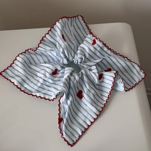 Détail d'un chouchou à rayures bleues avec broderie cœur rouge et bord ondulé