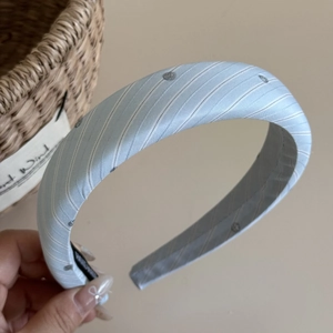 Detail eines hellblau gestreiften Haarreifs mit Silberglitzer und handgemachtem Etikett