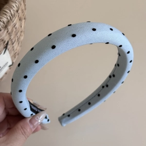 Detail eines hellblauen Polka-Dot-Haarreifs mit dickem Schwamm und Handmade-Label