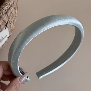 Nahaufnahme eines blauen Satin-Haarreifens mit glatter Stofftextur und dickem Design