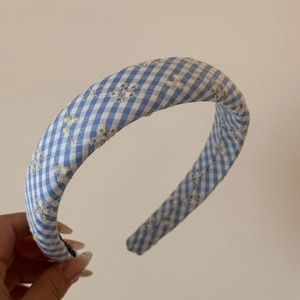 Détail d'un serre-tête à carreaux bleus avec broderie florale blanche et rembourré