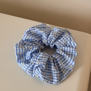 Détail du chouchou à carreaux bleus et blancs avec broderie délicate de fleurs blanches