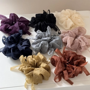 Flat lay of eight colorful chiffon bow scrunchies in purple, pink, and neutral tones