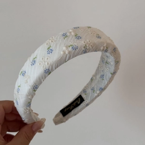 Détail de motifs floraux brodés sur un serre-tête blanc épais avec design bombé chic