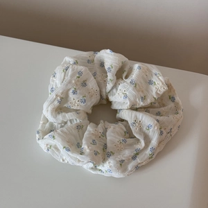 Détail de la broderie florale sur chouchou blanc avec motifs bleus et plis délicats