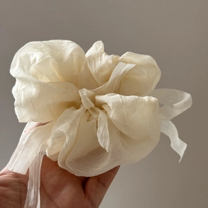 Close-up of a creamy white oversized chiffon bow scrunchie with layered fabric textures