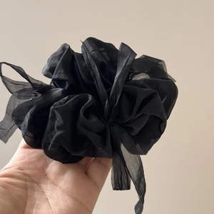 Detailed view of large black puff chiffon hair scrunchie with pleated organza texture