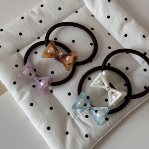 Detail of four acetate bow hair ties featuring inlaid pearls and a sparkling center rhinestone
