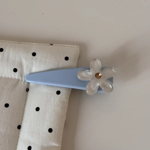 Détail d'une pince à cheveux bleu clair avec fleur en résine et cristal brillant