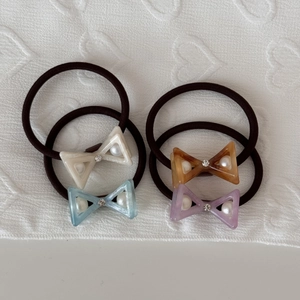 Set of four bow hair ties with rhinestones and pearls on a white textured background