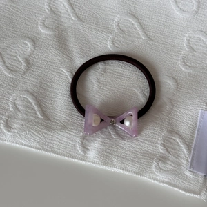 Close-up of purple acetate bow hair tie with white pearls and a sparkling rhinestone