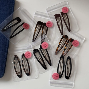Detail showing assorted leopard print and solid color teardrop hair clips in packaging