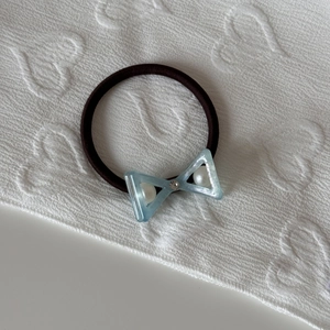 Close-up of light blue acetate bow hair tie with embedded white pearls and tiny rhinestone