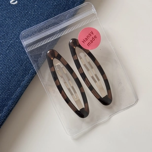 Close-up of leopard print hair clips set in transparent packaging with logo sticker