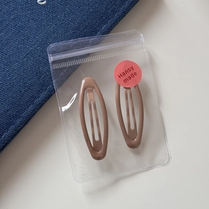 Detail of two matte leopard print drop hair clips packaged in a clear bag with a red label