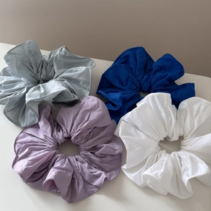 Detailed texture of oversized fabric scrunchies in gray, blue, purple, and white colors
