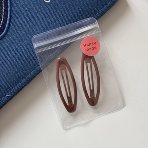Close-up of brown leopard pattern snap hair clips in a branded clear gift bag