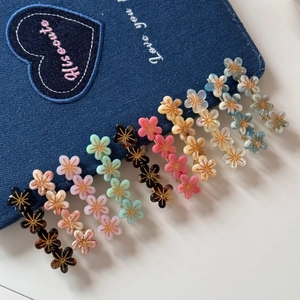Vue détaillée de barrettes fleurs en résine colorée avec centre doré sur denim