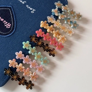 Détail de barrettes à fleurs colorées en rose et bleu sur un fond de tissu denim