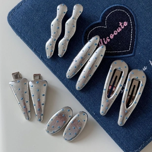 Détail de pinces à cheveux en cuir argenté à pois bleus sur fond de jean bleu