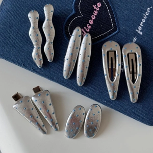 Vue détaillée de barrettes argentées à pois bleus aux formes géométriques de vagues et ovales