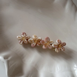 Gros plan détaillé sur une pince à cheveux fleurie marbrée rose et blanche dorée