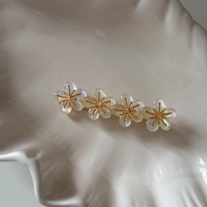 Vue détaillée d'une pince à cheveux à quatre fleurs nacrées sur un plateau coquillage