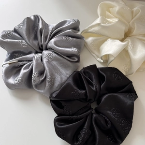 Close-up of rose jacquard satin scrunchies in grey, beige, and black colors