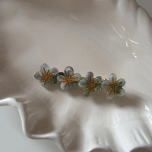 Détail de quatre barrettes à fleurs bleu clair avec centre doré sur plat en céramique