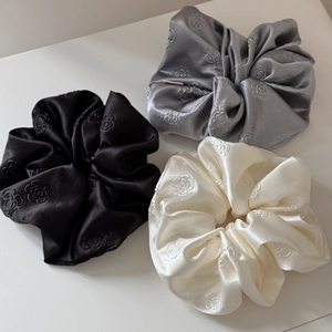 Set of three satin scrunchies with embossed rose patterns in black, silver, and cream